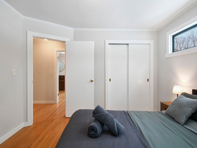 bedroom with ornamental molding, light hardwood / wood-style floors, and a closet