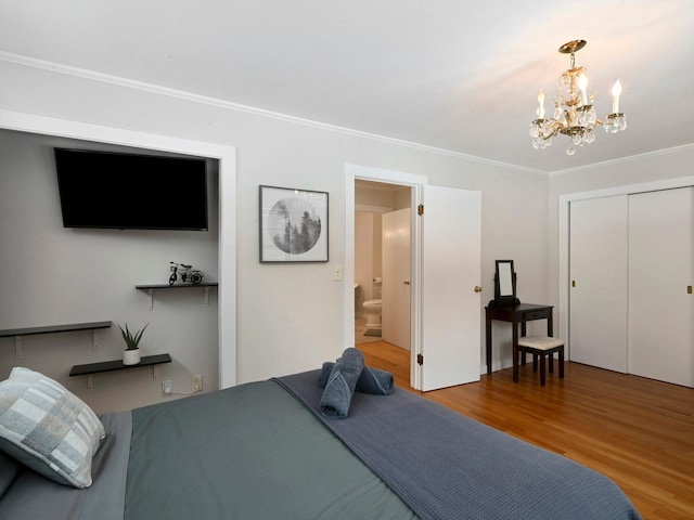 bedroom featuring ensuite bathroom, hardwood / wood-style flooring, crown molding, an inviting chandelier, and a closet