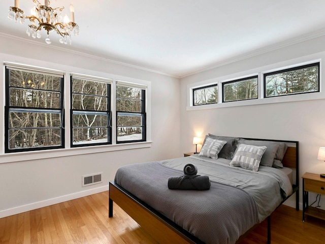 bedroom featuring hardwood / wood-style flooring, crown molding, and a notable chandelier