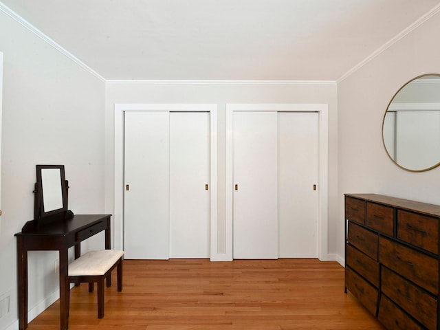 bedroom featuring multiple closets, ornamental molding, and light hardwood / wood-style flooring