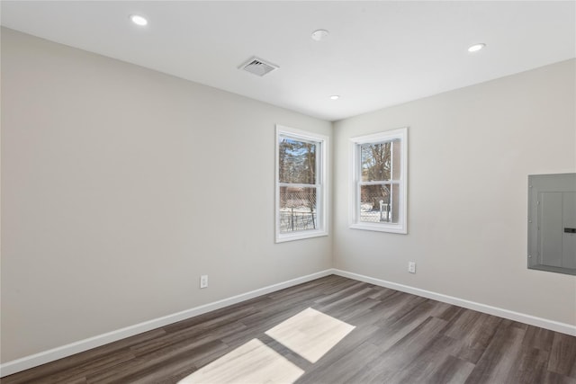 spare room with electric panel and dark hardwood / wood-style flooring