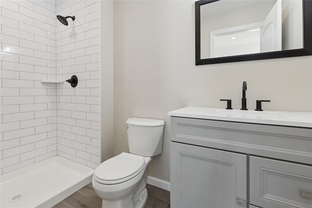 bathroom featuring tiled shower, vanity, toilet, and wood-type flooring