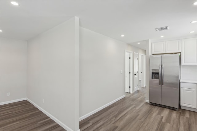 kitchen with white cabinetry, hardwood / wood-style floors, and stainless steel fridge