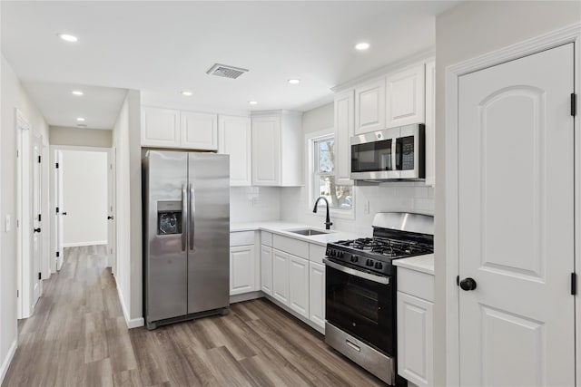 kitchen featuring appliances with stainless steel finishes, sink, white cabinets, and backsplash