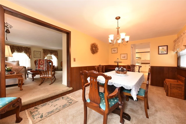 dining space with light carpet, a chandelier, and wood walls