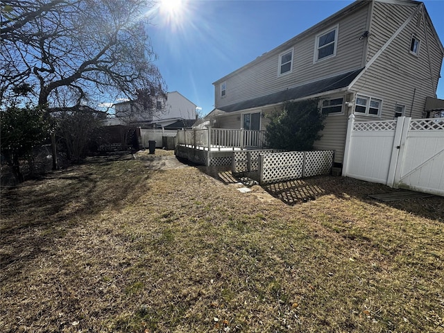 rear view of property with a wooden deck and a yard