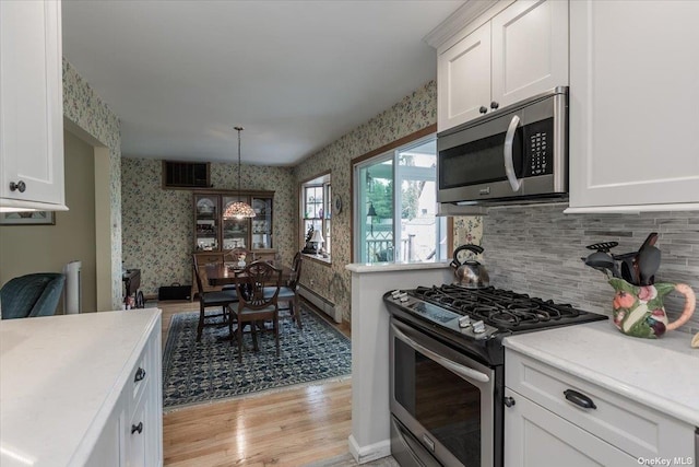 kitchen featuring white cabinetry, a baseboard radiator, hanging light fixtures, light hardwood / wood-style floors, and stainless steel appliances