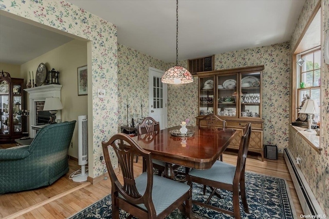 dining area featuring wood-type flooring and a baseboard heating unit