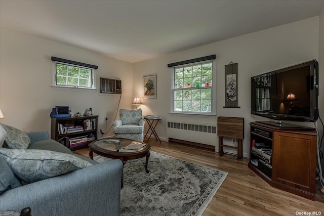 living room with a wall unit AC, plenty of natural light, radiator, and light hardwood / wood-style flooring