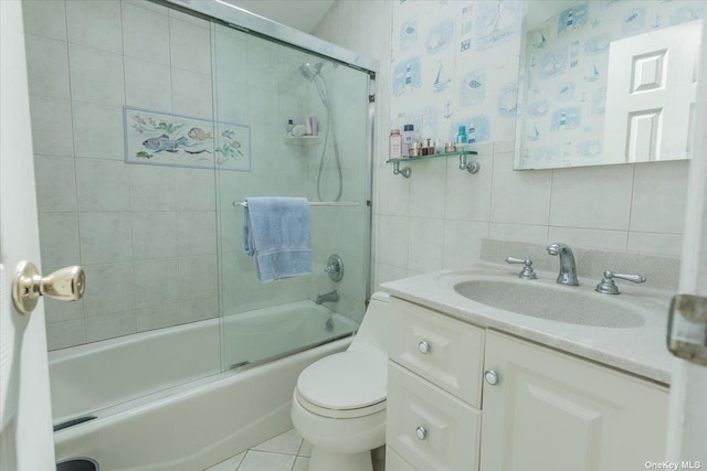 full bathroom featuring bath / shower combo with glass door, tile walls, vanity, toilet, and tile patterned floors