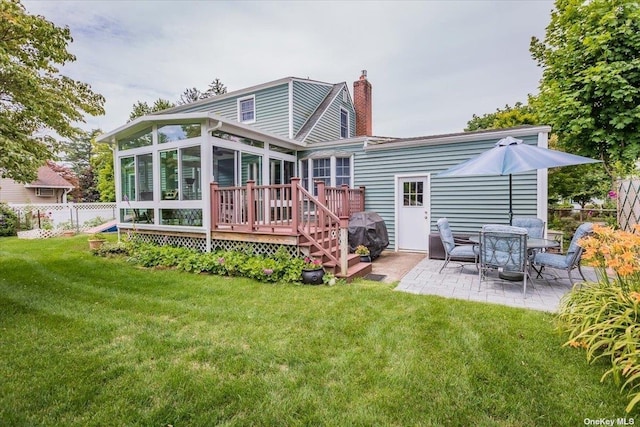 rear view of property featuring a patio area, a sunroom, a deck, and a lawn