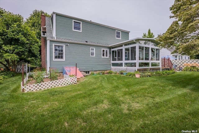 rear view of house with a lawn and a sunroom