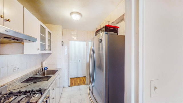 kitchen with stainless steel refrigerator, range, tile walls, backsplash, and white cabinets