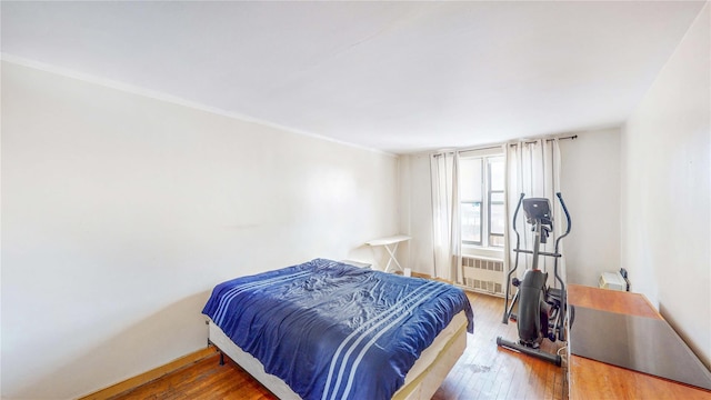 bedroom with hardwood / wood-style flooring and radiator heating unit