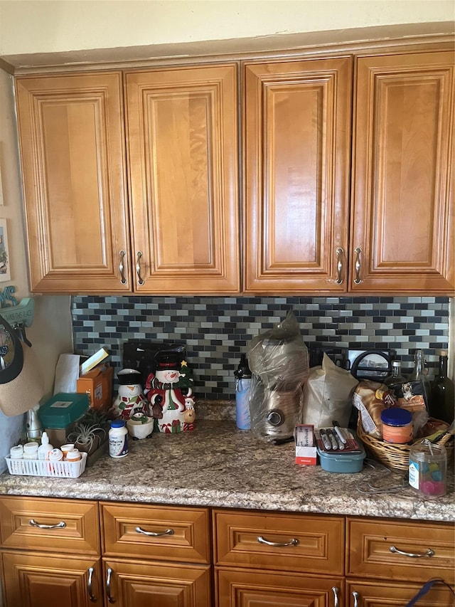 kitchen featuring light stone countertops, brown cabinetry, and backsplash