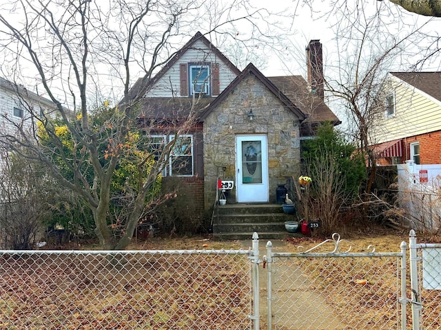 view of front facade featuring a gate, stone siding, a fenced front yard, and a chimney