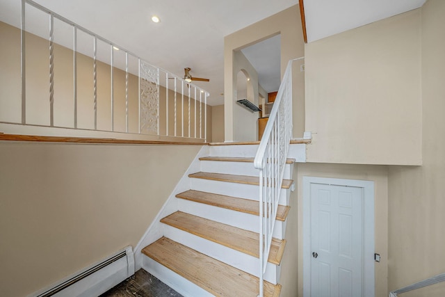 stairway with ceiling fan and a baseboard heating unit