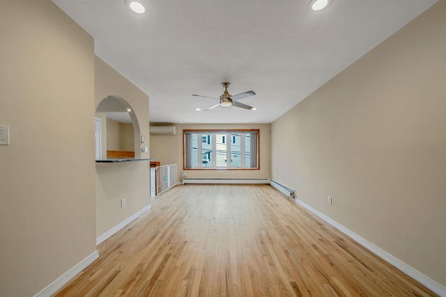 unfurnished living room featuring a baseboard heating unit, an AC wall unit, ceiling fan, and light wood-type flooring