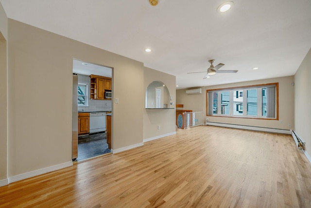 unfurnished living room featuring plenty of natural light, a baseboard heating unit, a wall mounted AC, and light hardwood / wood-style flooring