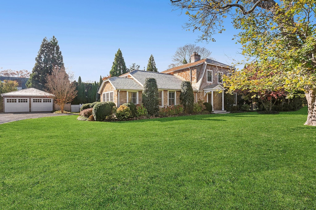 view of front of property with an outbuilding, a garage, and a front lawn