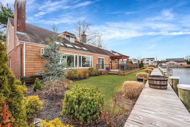 back of house with a gazebo, a deck with water view, and a yard