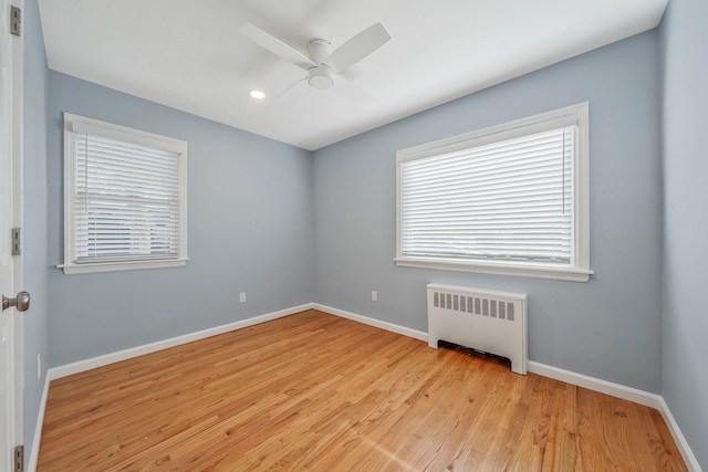 unfurnished room featuring ceiling fan, radiator, and light hardwood / wood-style floors