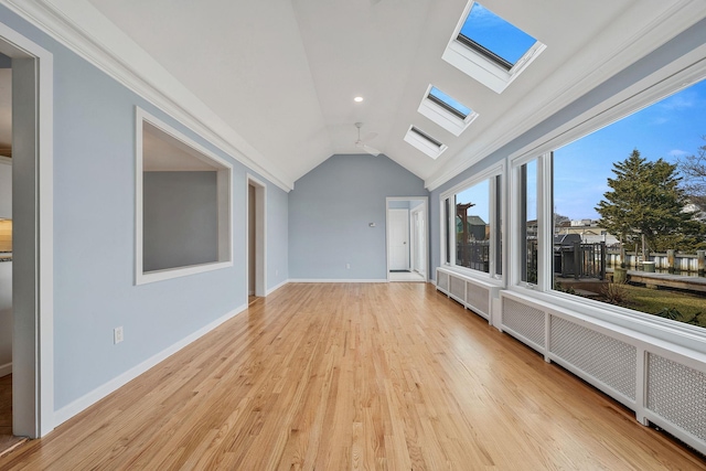 unfurnished living room with radiator, vaulted ceiling, and light wood-type flooring