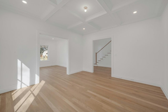 spare room featuring coffered ceiling, light hardwood / wood-style flooring, and beamed ceiling