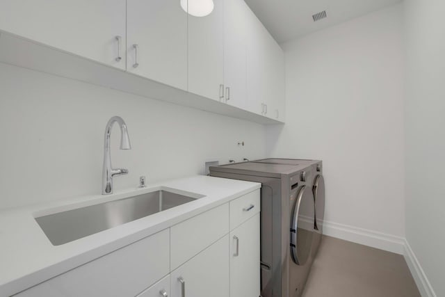 clothes washing area with cabinets, sink, and washer and dryer