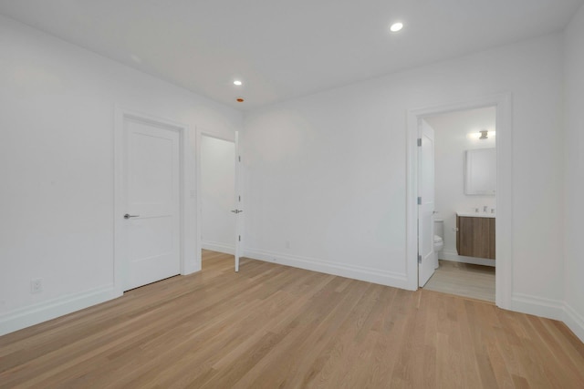 unfurnished bedroom with sink, ensuite bath, and light hardwood / wood-style floors