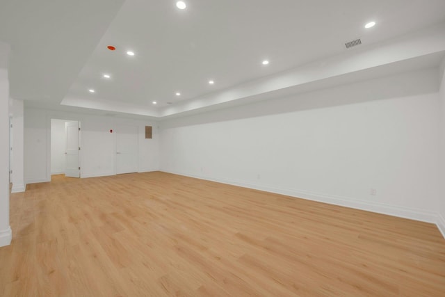 unfurnished room with light wood-type flooring and a tray ceiling