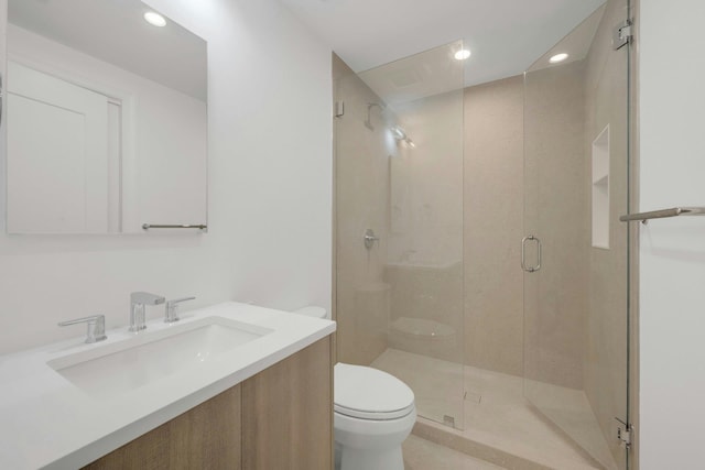 bathroom with vanity, toilet, and a shower with shower door