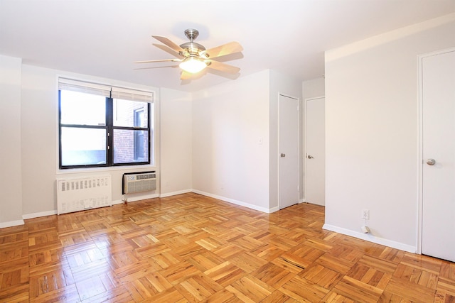 empty room with a wall mounted AC, radiator heating unit, light parquet flooring, and ceiling fan