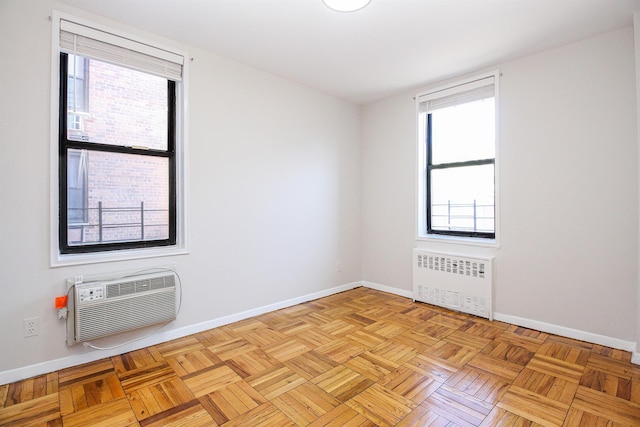 empty room with light parquet floors, a wall mounted AC, and radiator heating unit