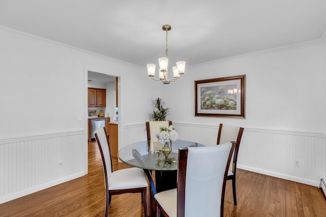 dining area with an inviting chandelier, hardwood / wood-style floors, crown molding, and a baseboard heating unit