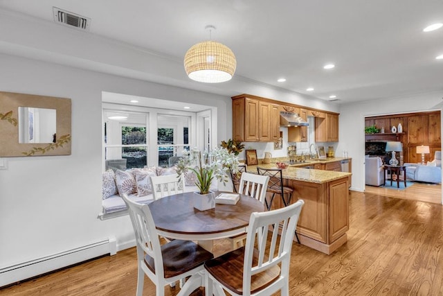 dining area featuring a baseboard heating unit, sink, and light wood-type flooring