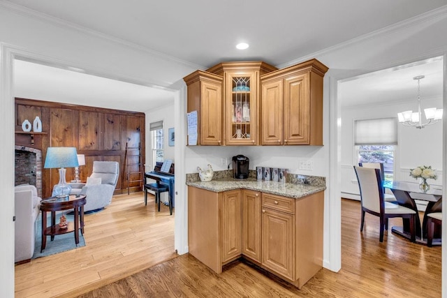 kitchen with crown molding, decorative light fixtures, and light hardwood / wood-style flooring