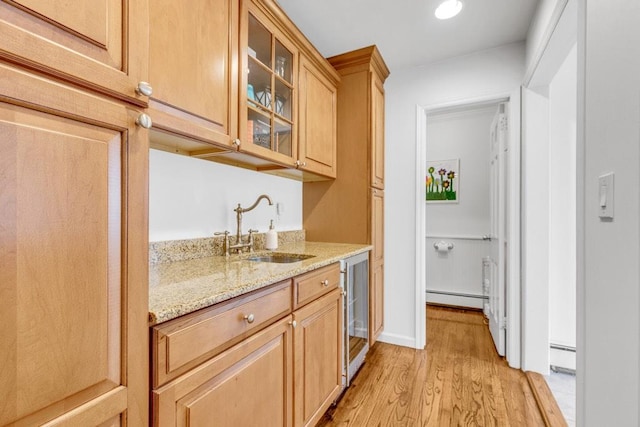 bar featuring light stone counters, sink, light hardwood / wood-style floors, and baseboard heating