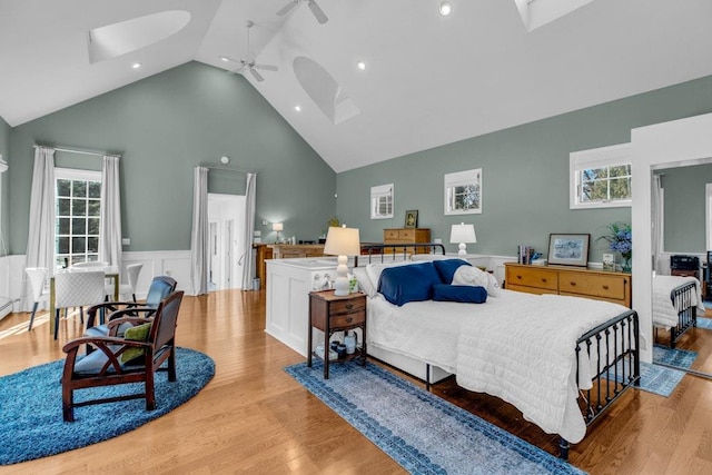 bedroom featuring ceiling fan, high vaulted ceiling, light hardwood / wood-style floors, and a skylight