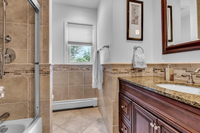 bathroom with tile patterned floors, shower / bath combination with glass door, tile walls, a baseboard radiator, and vanity