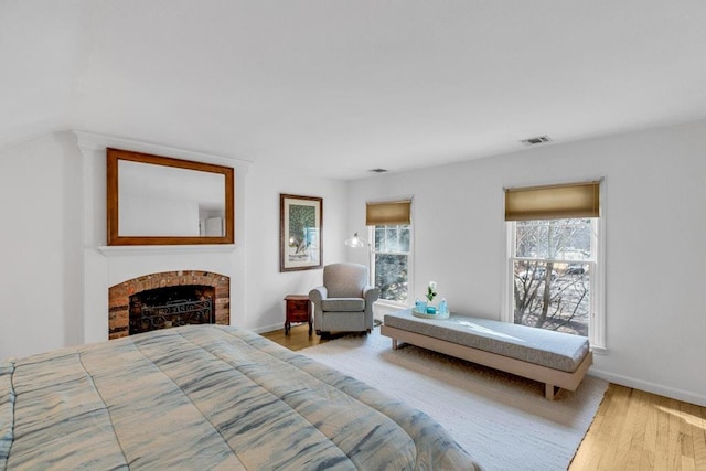 bedroom with light wood-type flooring and a fireplace