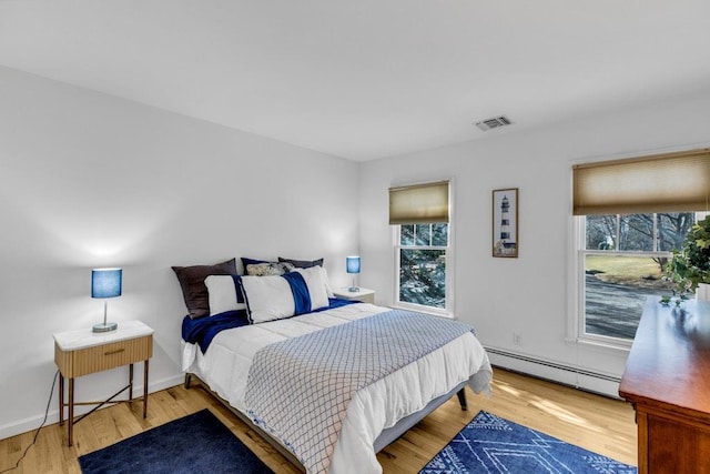 bedroom with a baseboard radiator and wood-type flooring