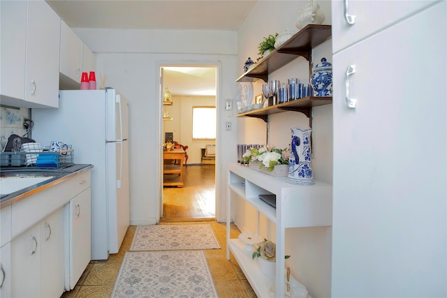 kitchen with white fridge, sink, and white cabinets