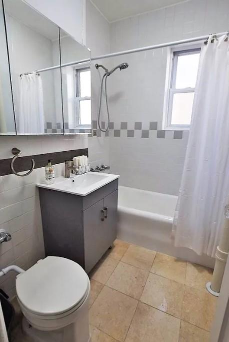 full bathroom featuring shower / tub combo, vanity, toilet, and tile walls