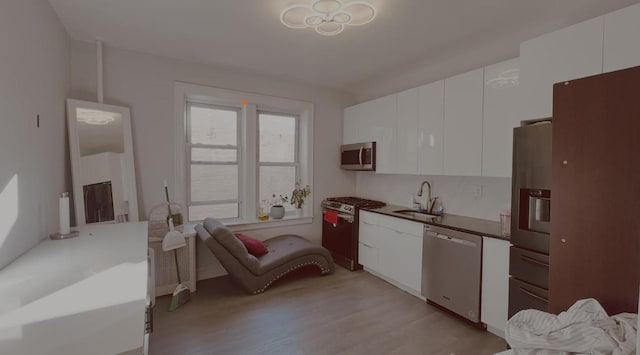 kitchen featuring white cabinetry, appliances with stainless steel finishes, sink, and light wood-type flooring