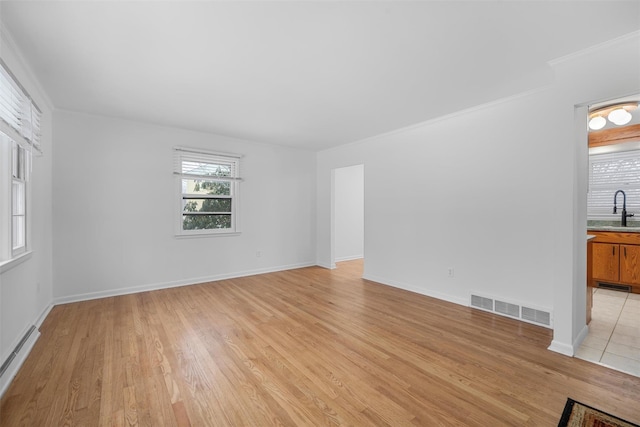 empty room featuring a baseboard radiator, sink, crown molding, and light hardwood / wood-style flooring