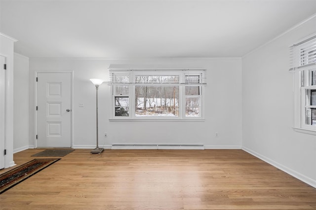 unfurnished room featuring baseboard heating, crown molding, and light wood-type flooring