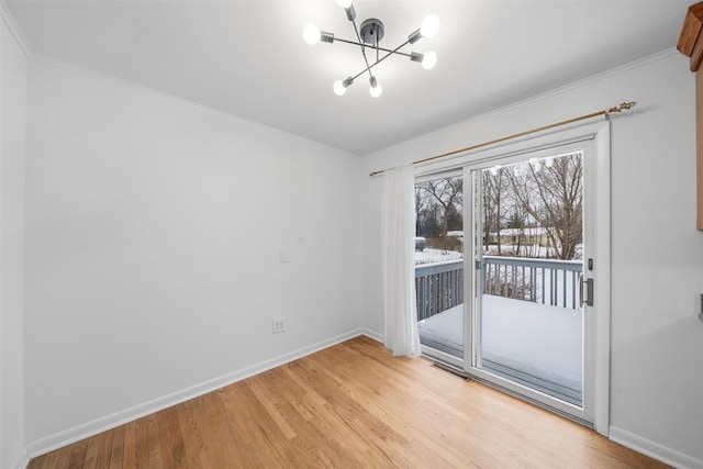 spare room featuring a notable chandelier, light hardwood / wood-style flooring, and ornamental molding