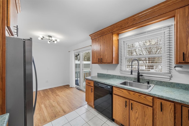 kitchen featuring dishwasher, sink, light tile patterned floors, and stainless steel fridge