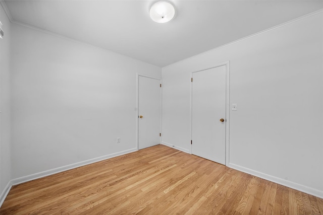 empty room with ornamental molding and light wood-type flooring